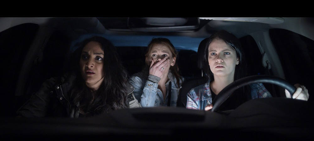 Still from "Dama Brana" - Amelia, Heather, and Jenna driving in the car at night, staring ahead in horror